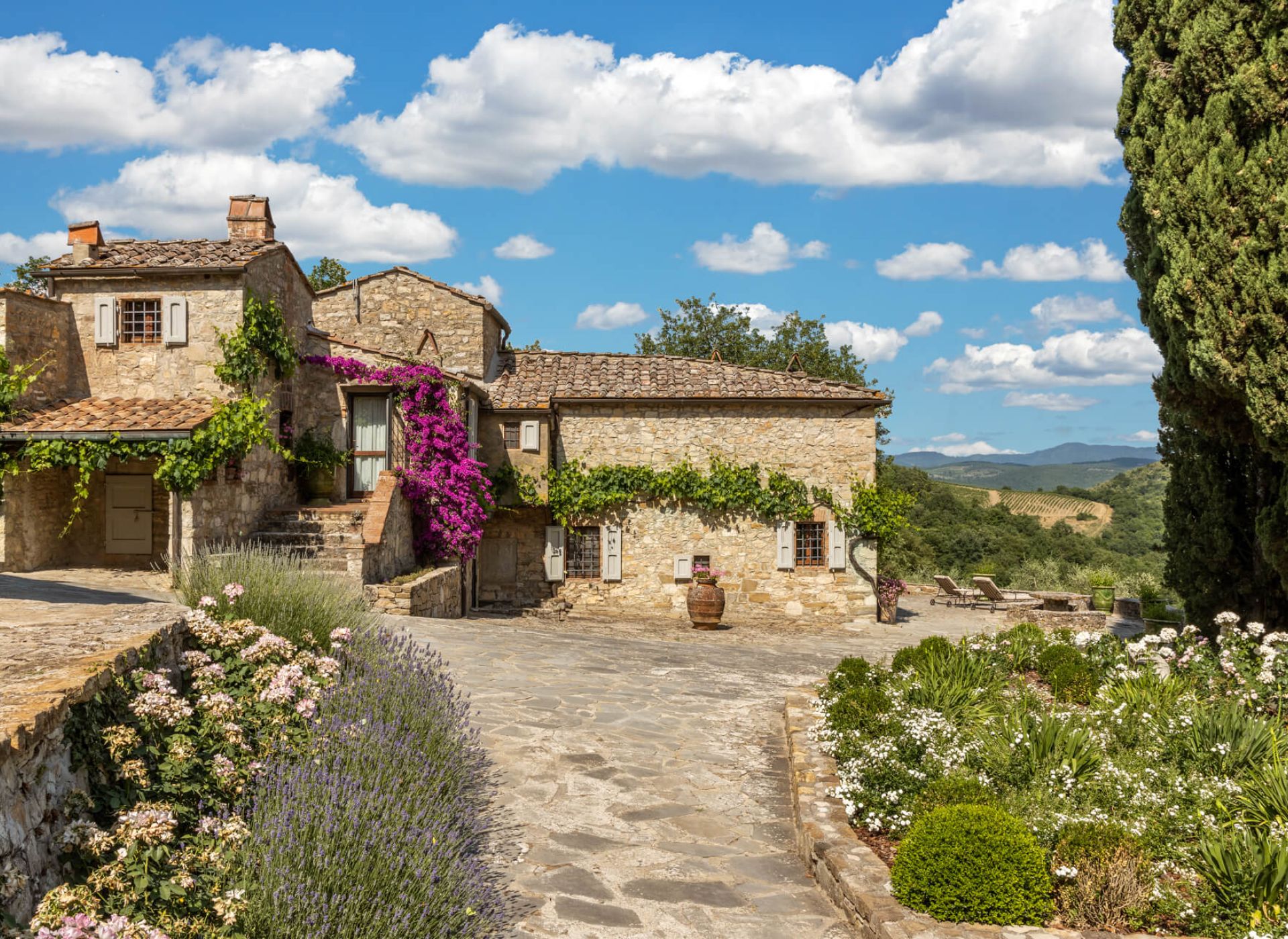 Stone farmhouse at Tenuta Ceccatelli surrounded by gardens and rolling Tuscan hills